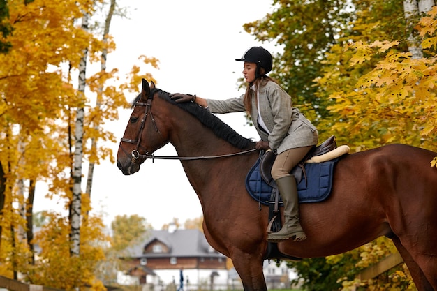 Retrato de una mujer joven y bonita con un día de otoño de equitación marrón