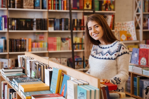 Retrato de una mujer joven y bonita eligiendo libros en la biblioteca