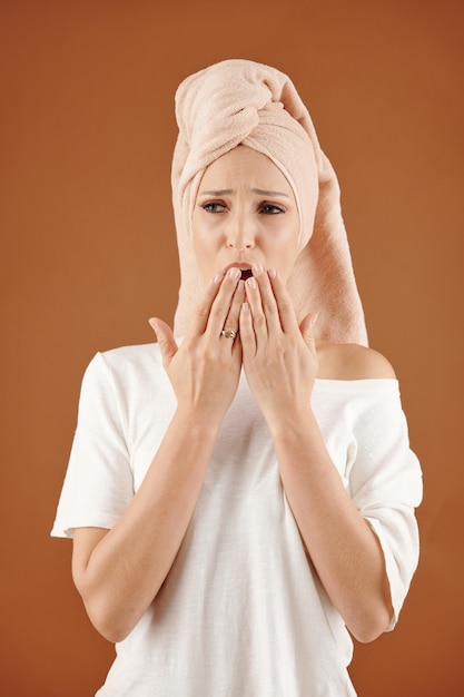 Retrato de mujer joven y bonita con una toalla en la cabeza bostezando al prepararse en la mañana