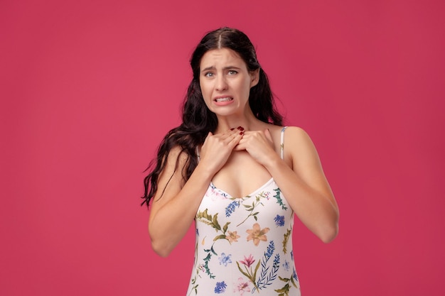 Retrato de una mujer joven y bonita con un vestido ligero de pie sobre fondo rosa en la gente del estudio desde ...