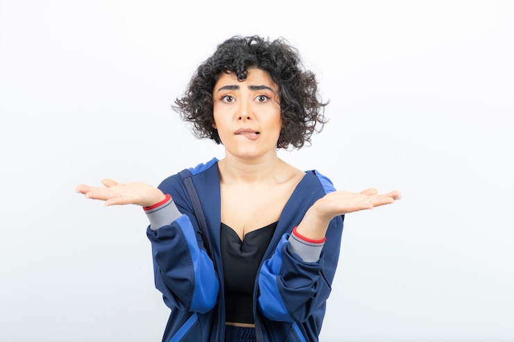 Foto retrato de una mujer joven con cabello rizado mostrando las palmas abiertas.