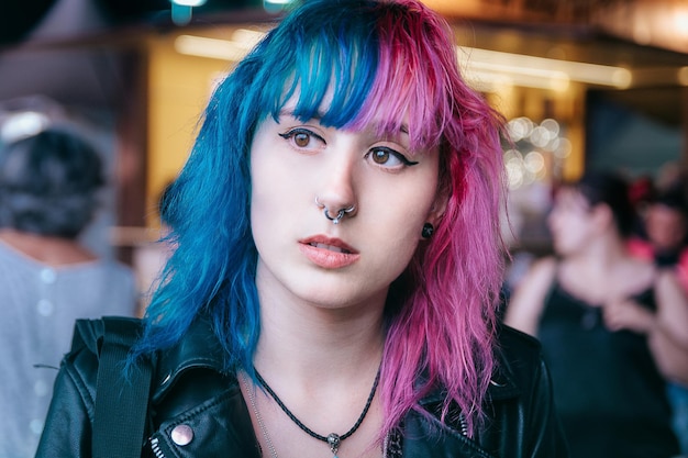 Retrato de una mujer joven con cabello rosa y azul con una expresión facial seria