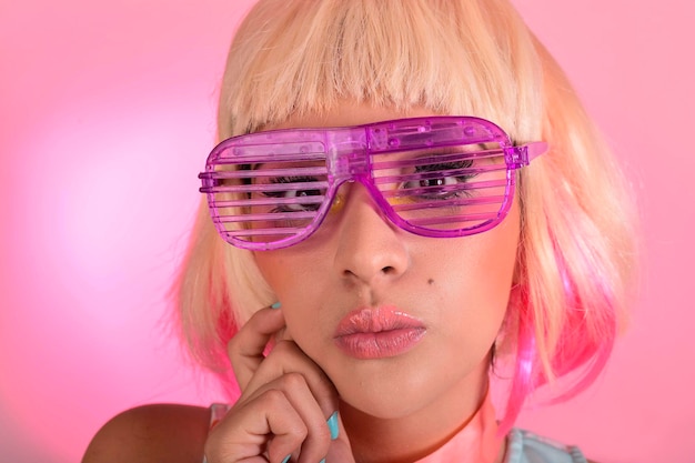 retrato de mujer joven con cabello rubio y fondo rosa con gafas de moda