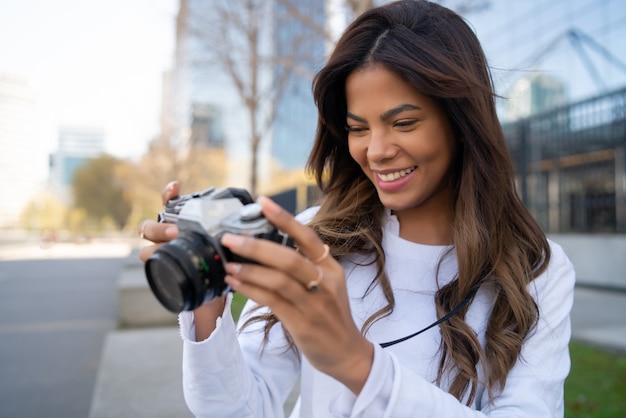 Retrato de mujer joven con cámara mientras toma fotografías en la ciudad. Nuevo concepto de estilo de vida normal.