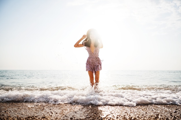 Retrato de mujer joven caminando por la playa al amanecer.