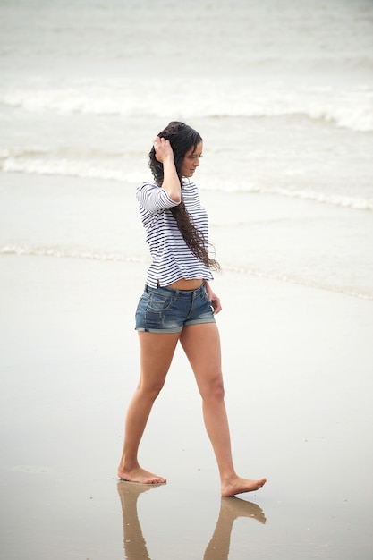 Retrato de una mujer joven caminando solo en la playa