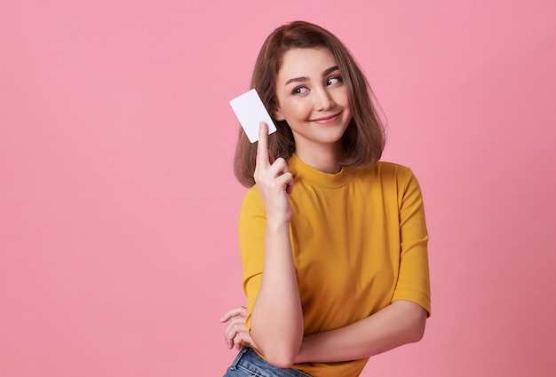 Retrato de una mujer joven en camisa amarilla que muestra una tarjeta de crédito