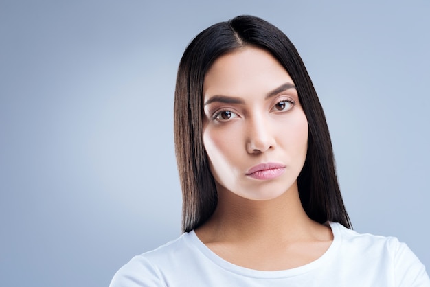 retrato, de, un, mujer joven, en, camiseta blanca, posar, contra, un, pared gris