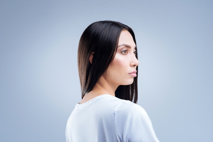 Foto retrato, de, un, mujer joven, en, camiseta blanca, posar, contra, un, pared gris