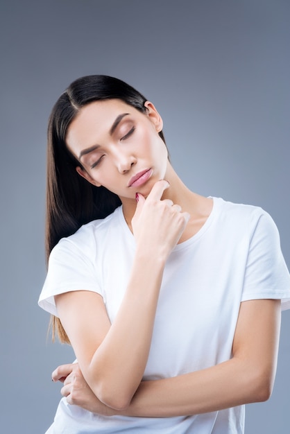 retrato, de, un, mujer joven, en, camiseta blanca, posar, contra, un, pared gris