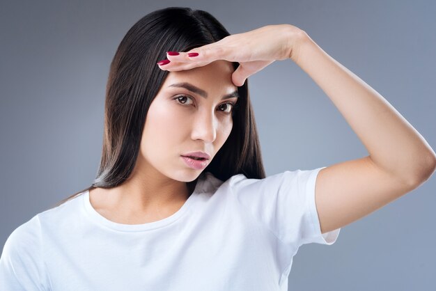 retrato, de, un, mujer joven, en, camiseta blanca, posar, contra, un, pared gris