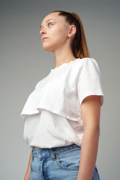 Retrato de una mujer joven con una camiseta blanca sobre un fondo gris