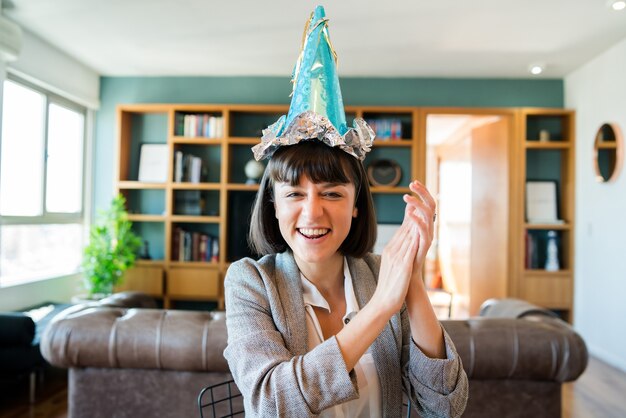 Retrato de mujer joven celebrando un cumpleaños en una videollamada desde casa.