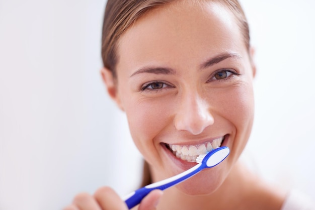 Retrato de mujer joven y cepillarse los dientes en el baño con una sonrisa, salud o autocuidado para la higiene, el aseo y la rutina Cepillo de dientes de niña y felicidad por limpiar una boca sana y comenzar la mañana