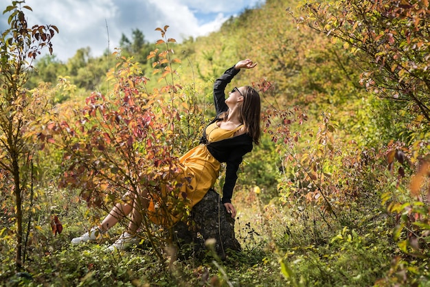 Retrato de mujer joven cerca de hojas de otoño en luz cálida