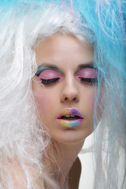 Retrato de mujer joven de cerca con maquillaje brillante y cabello creativo