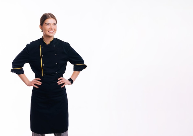 Retrato de mujer joven chef confiada feliz de pie sobre fondo blanco y mirando a otro lado