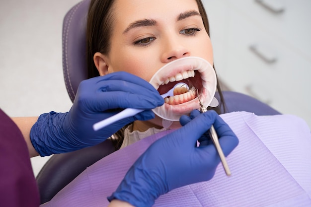 Retrato de una mujer joven en una clínica dental con guantes de goma haciendo un chequeo