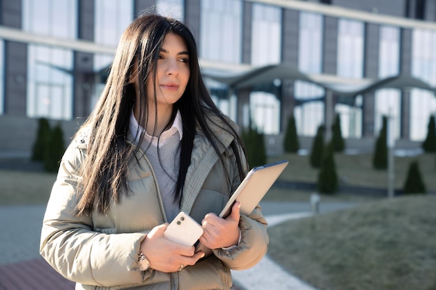 Retrato de una mujer joven con computadoras portátiles en el fondo de un edificio de oficinas