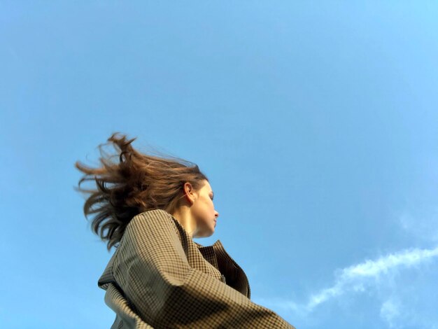 Foto retrato de una mujer joven contra el cielo azul