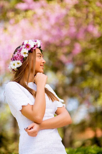 Retrato de mujer joven con corona de flores frescas en la cabeza