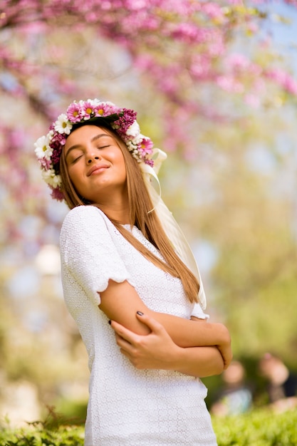 Foto retrato de mujer joven con corona de flores frescas en la cabeza.