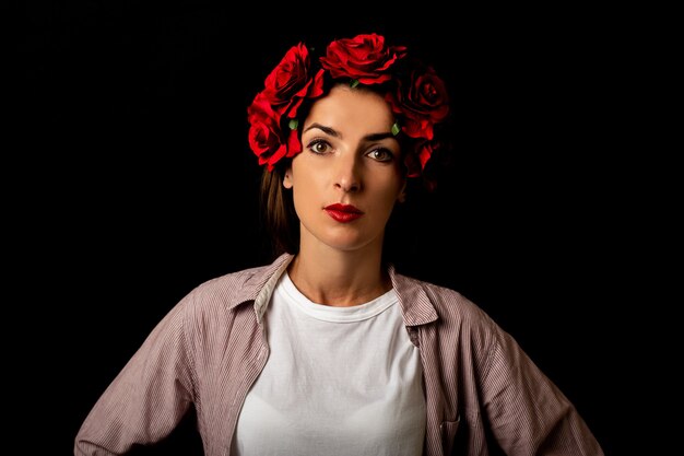 Retrato de una mujer joven en una corona de flores rojas