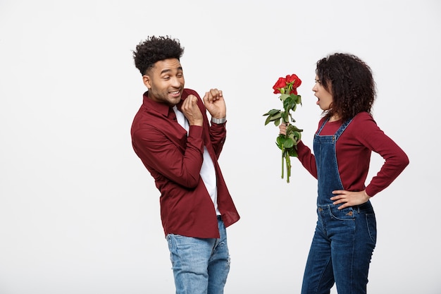 Retrato de una mujer joven decepcionada que sostiene la rosa roja mientras que está enojado con su novio.