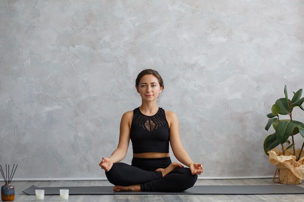 Retrato de mujer joven deportiva haciendo ejercicios en la lección de yoga en casa.