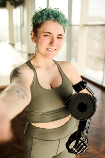 Retrato de mujer joven con discapacidad haciendo retrato selfie mientras entrena en el gimnasio