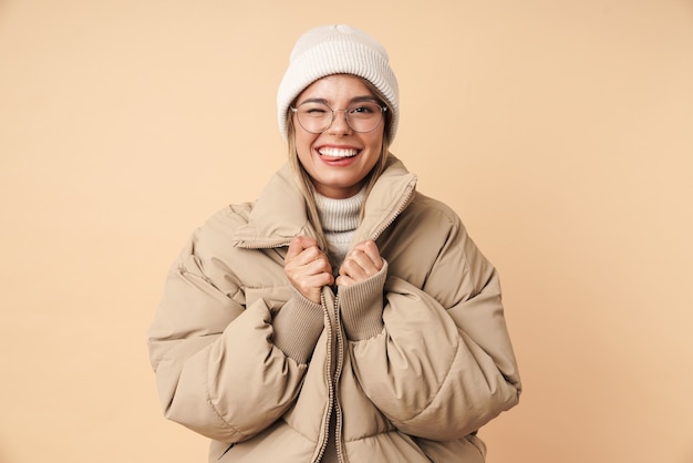 Retrato de mujer joven divertida en abrigo de invierno guiñando un ojo y sonriendo