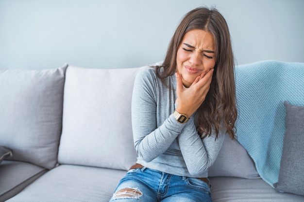 Foto retrato de una mujer joven en dolor con un dolor de muelas