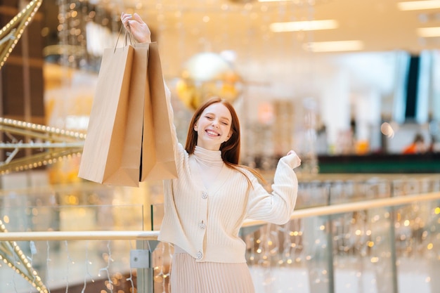 Retrato de mujer joven emocionada feliz con los ojos cerrados sosteniendo bolsas de compras con compras y