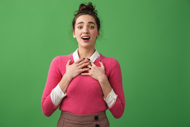 Retrato de una mujer joven emocionada gritando aislado sobre verde