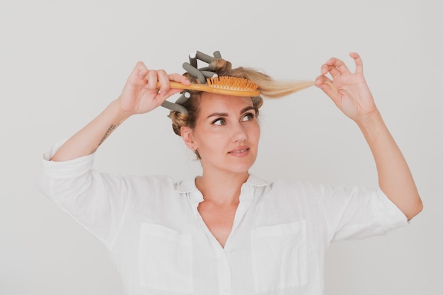 Retrato de mujer joven encantadora en rizadores de pelo y cepillo para el pelo.