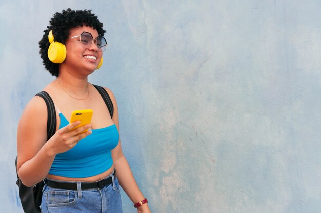 Retrato de una mujer joven de un entorno urbano escuchando música con auriculares