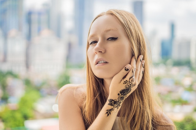 Retrato de una mujer joven en estilo casual con mehendi en el contexto de una gran ciudad