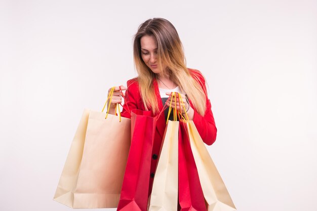 Retrato de mujer joven con estilo feliz con bolsas de la compra en traje rojo