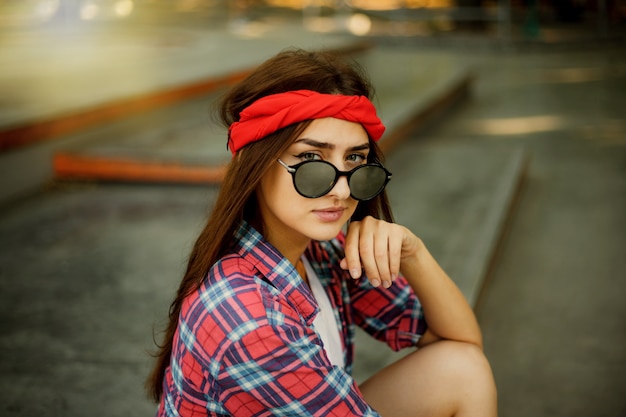 Foto retrato de mujer joven con estilo en gafas de sol espejadas en skatepark