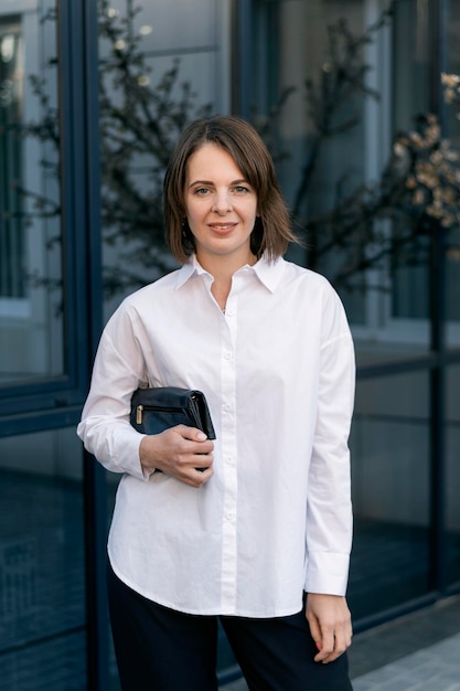 Retrato de mujer joven con estilo en ropa de negocios Camisa formal y embrague negro Estilo casual