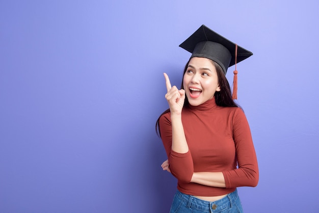 Retrato de mujer joven estudiante universitaria con gorro de graduación en violeta