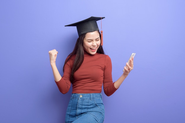 Retrato de mujer joven estudiante universitaria con gorro de graduación en violeta