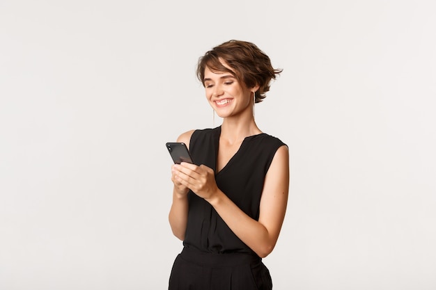 Retrato de mujer joven exitosa sosteniendo smartphone y sonriendo