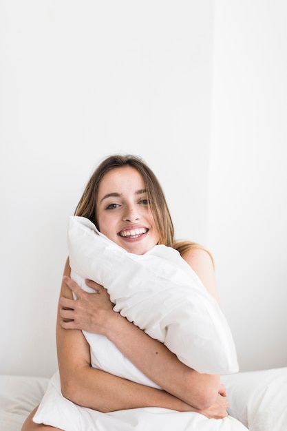 Retrato de una mujer joven feliz abrazando la almohada