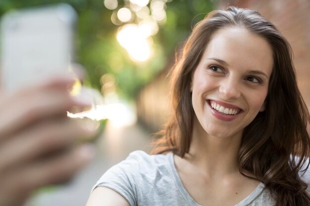 Retrato de mujer joven feliz al aire libre tomando un selfie