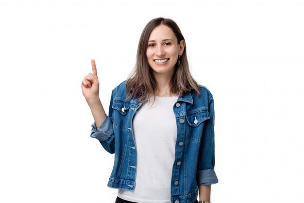 Retrato de mujer joven feliz apuntando hacia arriba sobre fondo blanco.