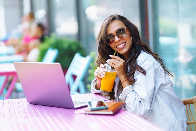 Retrato de mujer joven feliz con una computadora portátil en el café Freelancer trabajando en una computadora portátil Negocios en línea