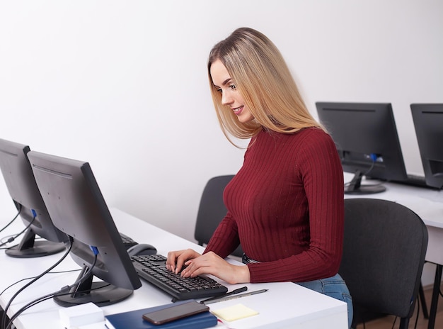 Retrato de la mujer joven feliz de la empresaria cerca en la pared blanca