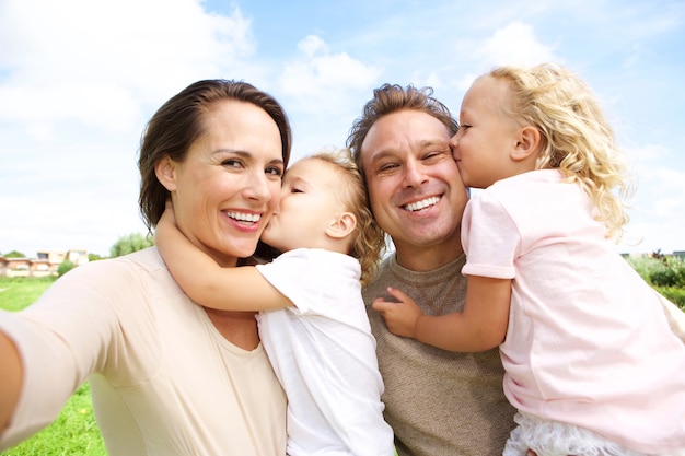 Retrato de mujer joven feliz hablando selfie de su familia al aire libre