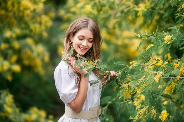 Retrato de una mujer joven feliz con una mimosa.